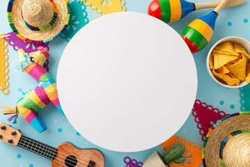 Cinco de Mayo photo from top view, featuring essentials like sombreros, vihuela, maracas, cactus, a bright pinata, flag bunting, and nachos on a soft blue background, circular space for writing