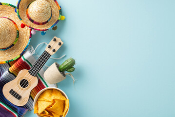 Cinco de Mayo setup from top view, featuring iconic accessories like sombreros, vihuela, cactus, a bright serape, and nachos, placed on a pastel blue canvas with area for text