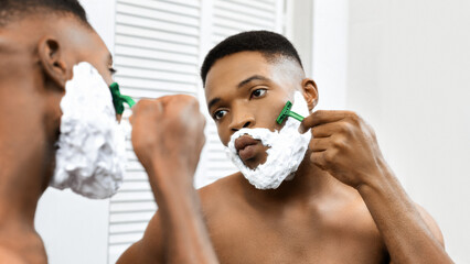 Man shaving in front of the mirror in bathroom