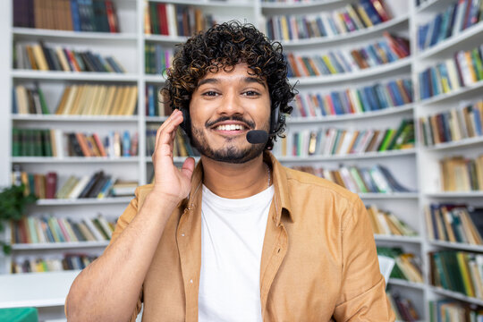 A cheerful young man wearing a headset and smiling as he looks at the camera, likely engaging in a video call or as a student in a virtual class.