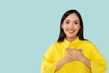 Cheerful happy thankful hispanic young casual woman holding hands on chest and smiling at camera
