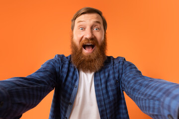 Obraz premium Excited Man With Red Beard Shouting Spreading Hands, Orange Background