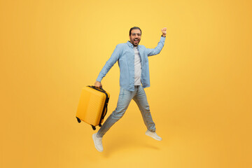 Fototapeta na wymiar Man jumping with suitcase on yellow background