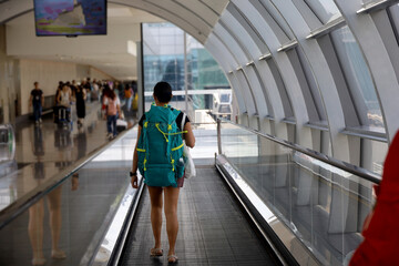 Rear view of traveler with big backpack or backpacker walking in airport hall, traveler concept