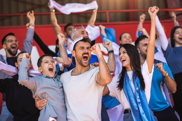 Football / soccer fans are cheering for their team at the stadium on the match - obrazy, fototapety, plakaty