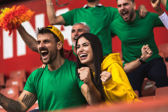 Football / soccer fans are cheering for their team at the stadium on the match.