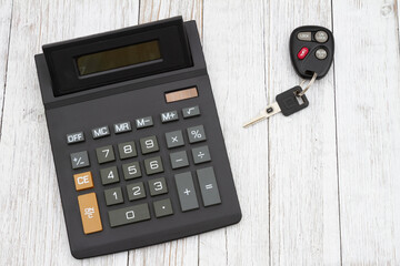 A black calculator with car keys on wood desk - 772225728