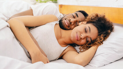 Couple cuddling peacefully in their sleep in bed