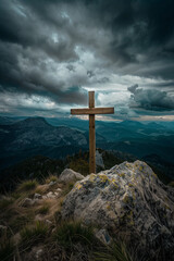 A wooden cross atop a mountain, with dark clouds in the sky and mountains behind it