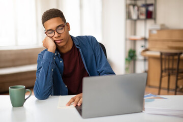 Bored young man with laptop in casual home setting