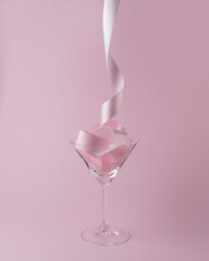 Martini glass with pink party ribbon. Minimal celebration concept.