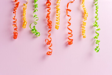 Colorful party streamers on pink background. Minimal celebration concept. Flat lay.