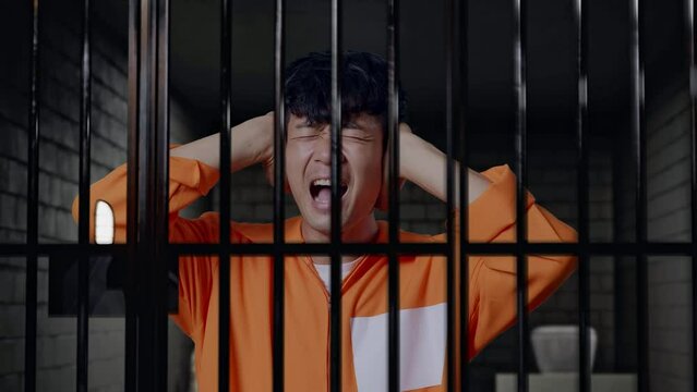 Close Up Of Stressed Asian Male Prisoner Screaming Loud While Standing In Prison