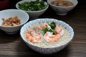 Shrimp Boiled rice soup or shrimp porridge in a bowl and pickle turnip,  coriander, and deep-fried garlic and oil on wooden table