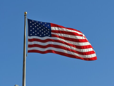 A large American flag is flying in the sky. The flag is red, white, and blue and has stars on it. The flag represents the United States