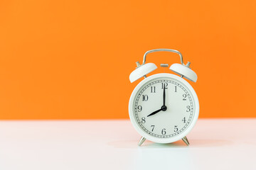Alarm white vintage alarm clock with orange color background, copy space for tex.  Morning and Start up Concept