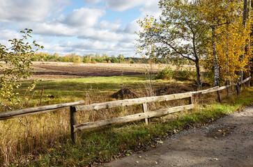 Fototapeta na wymiar Old wooden fence against a sky on a sunny day. Beautiful summer or autumn rural landscape
