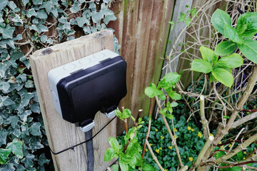 Newly installed double AC power sockets seen fitted with a weather proof cover. Seen in a garden...