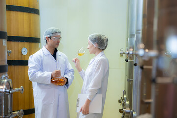 Mature female and male researchers and developers working in winery, Testing wine that has been...