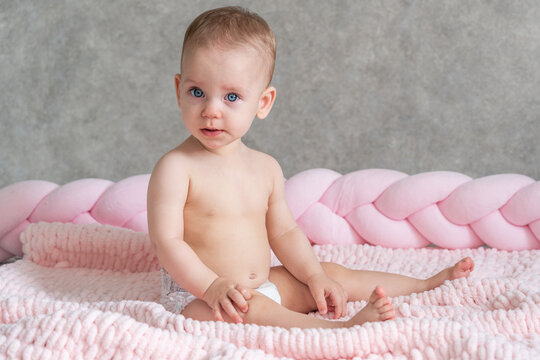 The baby sits on the bed and just looks at the camera. Universal photo