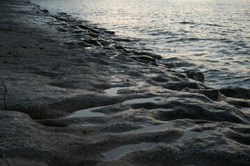 Sandy beach shoreline with an array of stones scattered along the coastline, Greece