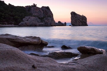 Sandy beach shoreline with an array of stones scattered along the coastline, Greece