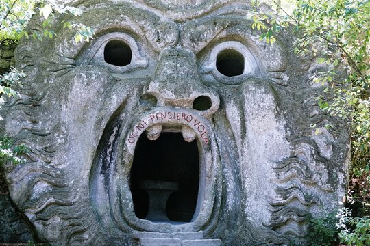 Bomarzo, Viterbo, Lazio, Italy - 08.25.2020: Orcus mouth sculpture at famous Parco dei Mostri (Park of the Monsters), also named Sacro Bosco (Sacred Grove) or Gardens of Bomarzo in Bomarzo
