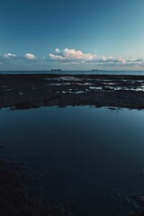Fototapeta premium Sunset reflecting clouds on the ocean's surface seen from a beach vantage point