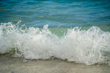 Fototapeta premium Ocean waves crashing against a sandy shore.