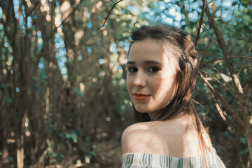 Chica hermosa y sonriente posa en el bosque