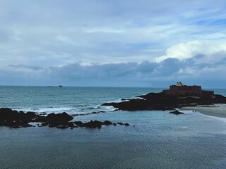 Beautiful seascape with a small rocky isle with a fort on a cloudy day