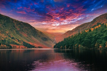 Picturesque landscape of a tranquil mountain range and a lake illuminated by a beautiful sunset
