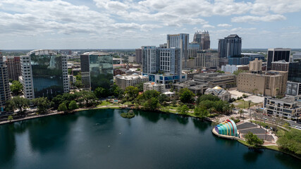 Obraz premium Downtown Orlando skyline overlooking the tranquil Lake Eola Park with its iconic fountain and urban backdrop.
