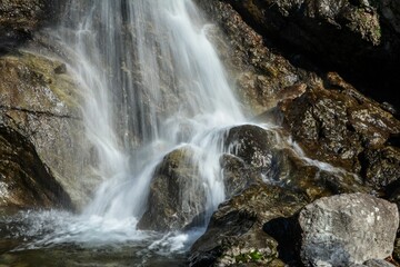 Fototapeta premium Majestic waterfall cascading down a rocky mountain with lush moss growing on the rocks
