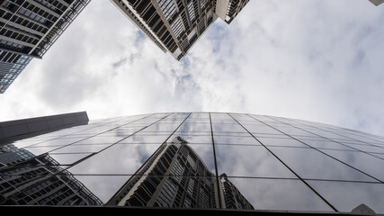 clouds flowing over high buildings. 4K glass buildings with cloudy blue sky background Low angle of...