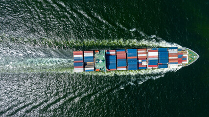 Aerial view of cargo ship with contrail in the ocean sea ship carrying container and running from container international port smart freight shipping by ship service.