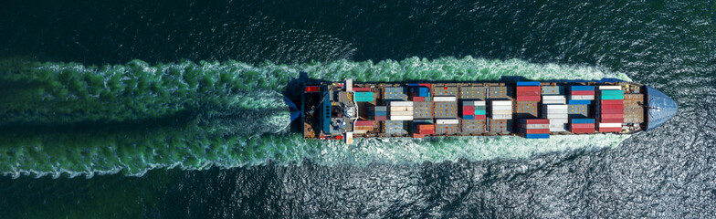 Aerial top view of cargo ship with contrail in the ocean sea ship carrying container and running from container international port smart freight shipping by ship service.