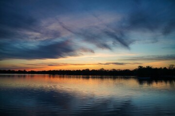Obraz premium Idyllic landscape of a lake illuminated in a warm, orange light by the setting sun.
