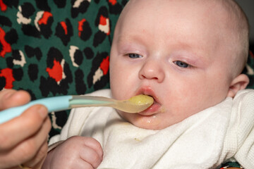 bébé mangeant son petit pot à la petite cuillère dans les bras de maman