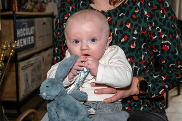 bébé dans les bras de sa mère avec son lapin doudou bleu