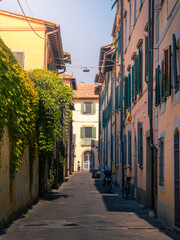 Narrow empty medieval street of European city with old colorful residential buildings, Pisa, Italy