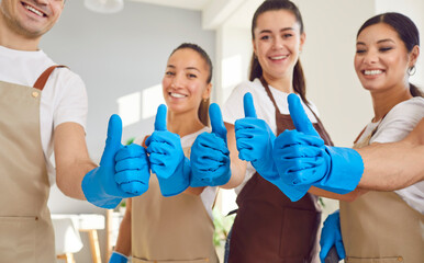 Close up of the hands of a cleaning staff team, wearing gloves and giving a thumbs up. The group of...