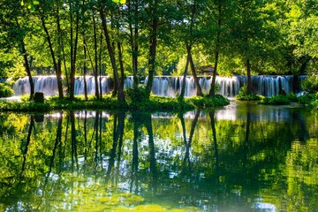 Majestic waterfall cascades to a river of emerald green water in Jajce, Bosnia and Herzegovina
