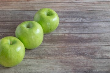 Tree fresh green apples on the wooden tabletop