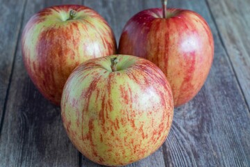 Bright red apples resting on a light wooden surface