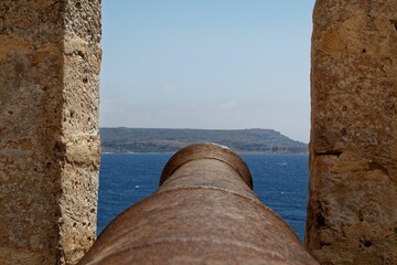 Vintage cannon pointing towards the horizon in a picturesque seascape of Malta