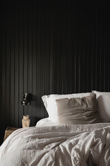 A bedroom wall with vertical black paneling, creating an elegant and minimalist backdrop for the bed linen. The wall is a dark grey color, adding depth to the space.