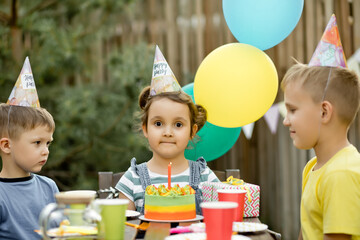 Beautiful adorable six year old girl celebrating her birthday with family or friends, blowing...