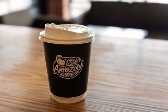 Pattaya, Thailand - 24 December, 2023: Coffee to go from cafe Amazon brand. Paper cup on table indoors. Cafe Amazon is a global Thai chain of coffee shops
