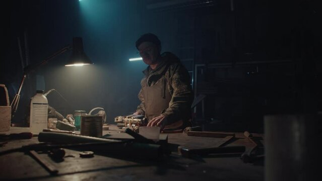 A man builds a bomb in his workshop at night
